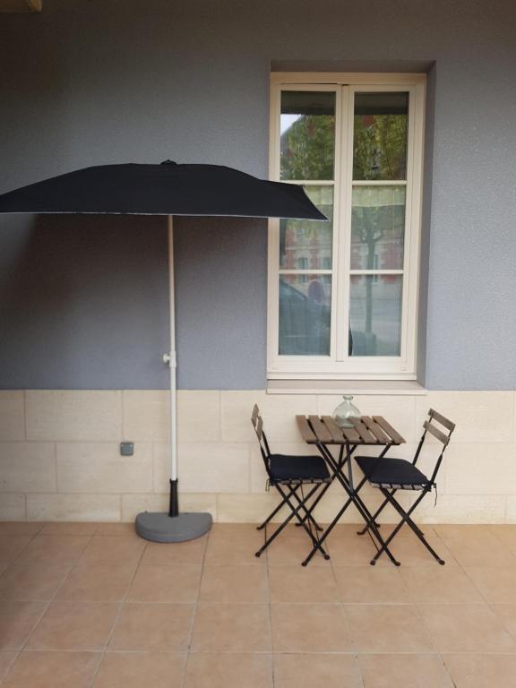 a table and chairs with an umbrella in a room at Appt plein coeur de Soulac sur Mer in Soulac-sur-Mer