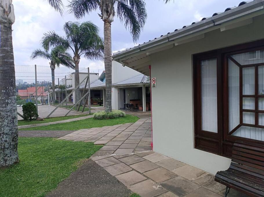 a building with a bench next to a palm tree at Apartamento em Bento Gonçalves-RS in Bento Gonçalves