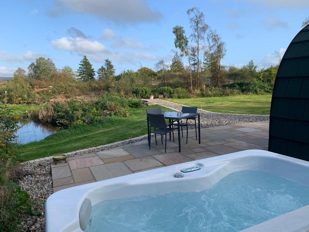 a jacuzzi tub with a table and chairs on a patio at Red Squirrel Pod with Hot Tub in Oban