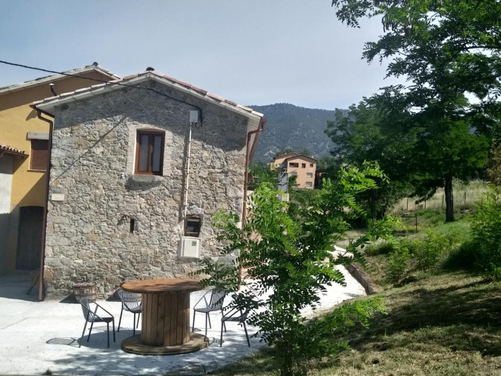 a table and chairs in front of a stone building at LES ROVILES in Sant Pere de Torelló
