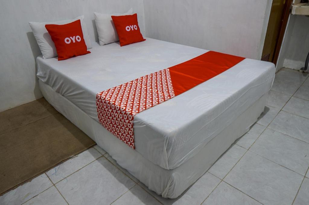 OYO 93161 Nurul Hikmah Homestay Syariah & Sport Center في Sedati: سرير ومخدات حمراء عليه في غرفة