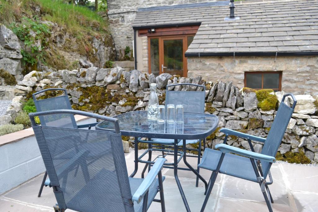 a glass table and chairs on a patio at Ashes Farm - Ingleborough View cottage in Settle