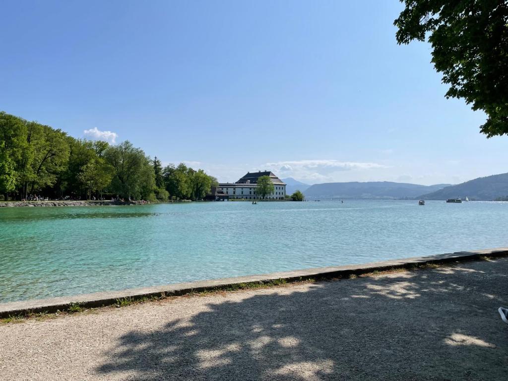 una vista de un lago con una casa a lo lejos en Fewo Maiberger, en Schörfling am Attersee