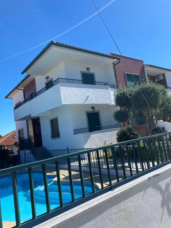 a white house with a fence next to a swimming pool at Casa da Leonor in Viseu