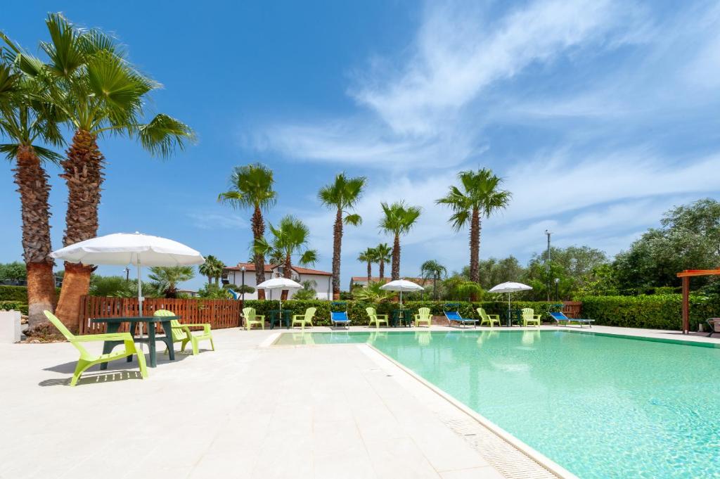 a swimming pool with chairs and umbrellas and palm trees at Residence Martino - Casa Vacanze in Castelnuovo Cilento