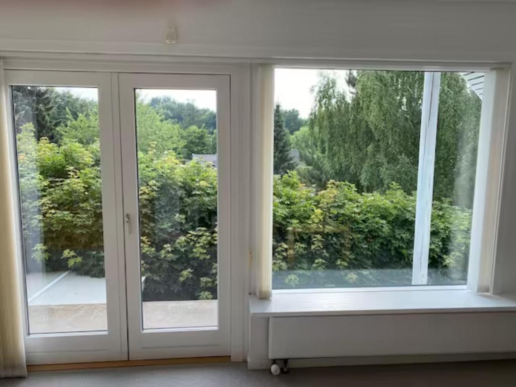 pusty pokój z dwoma oknami i parapetem w obiekcie Apartment near nature w mieście Birkerød