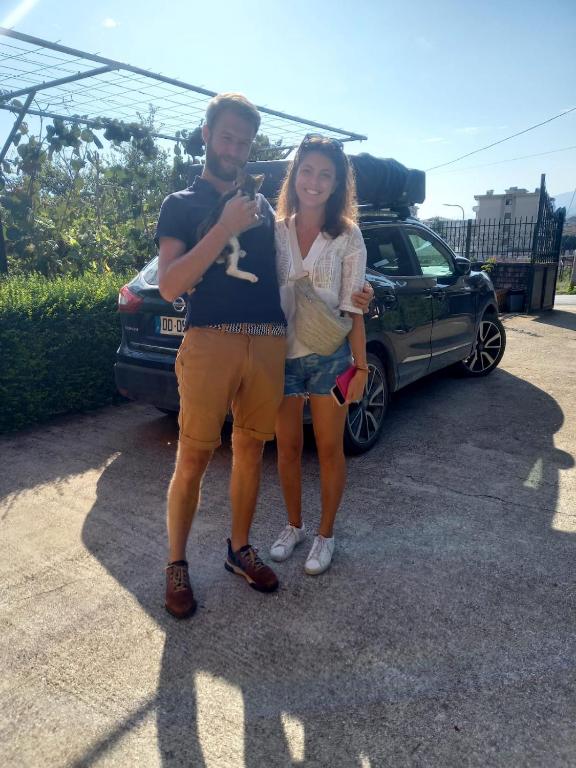 a man and a woman standing next to a car at GuestHouseMantho in Gjirokastër