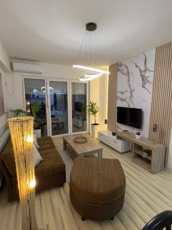 La Maison Apartment Skopje في إسكوبية: غرفة معيشة مع أريكة وتلفزيون