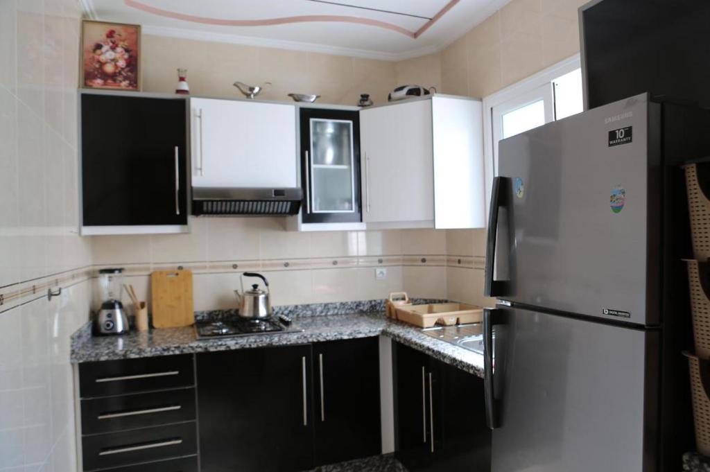 eine Küche mit schwarzen und weißen Schränken und einem Kühlschrank in der Unterkunft Hhhhhhhhhh in Asilah