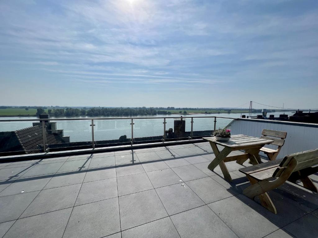 a balcony with a table and a view of the water at PANORAMA - Exklusives Apartment an der Promenade mit Dachterrasse & Rheinblick in Emmerich