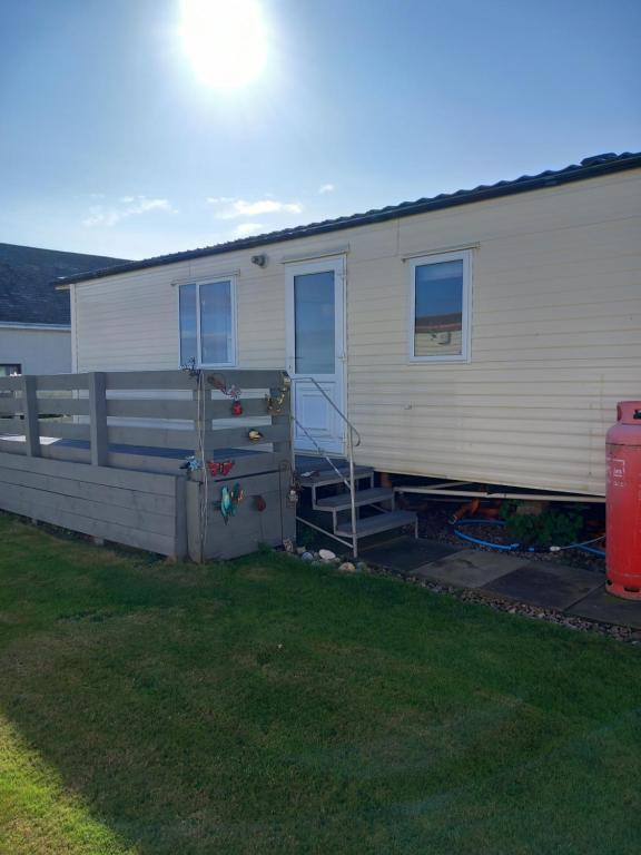 a mobile home with a fence and a yard at Melody Brooks Caravan Park Caravan number 22 in Portknockie