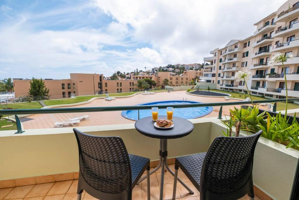 balcón con mesa, sillas y piscina en Sarah's Apartment by GALMI, en Caniço