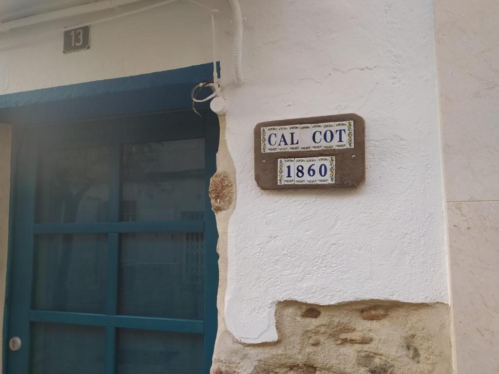 un cartello sul lato di un edificio con una porta di CAL COT a Hospitalet de l'Infant