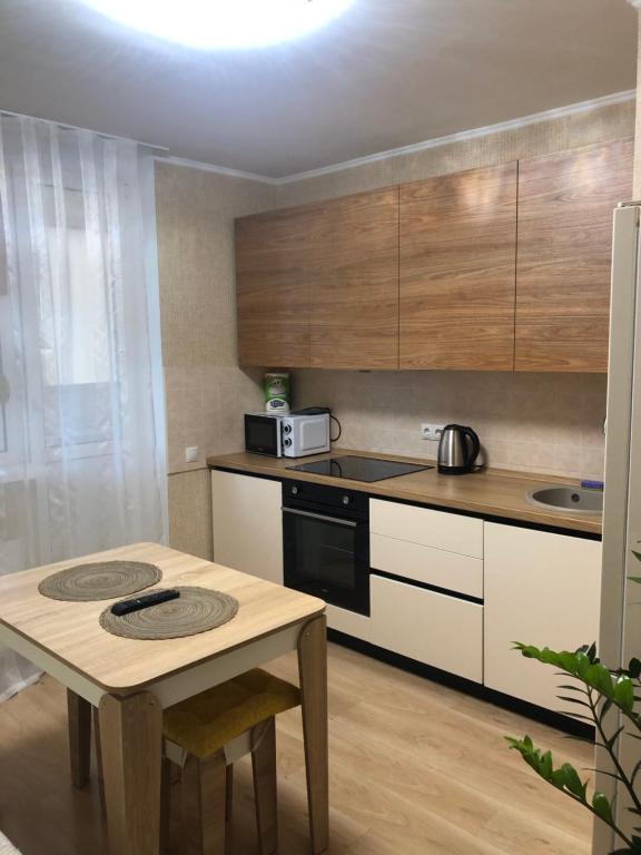 eine Küche mit einem Tisch, einer Mikrowelle und einem Herd in der Unterkunft Квартира по вулиці Набережна in Wyschhorod