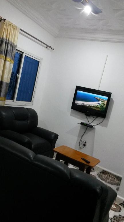 a living room with a couch and a tv on a wall at LMD Apartments in Kololi