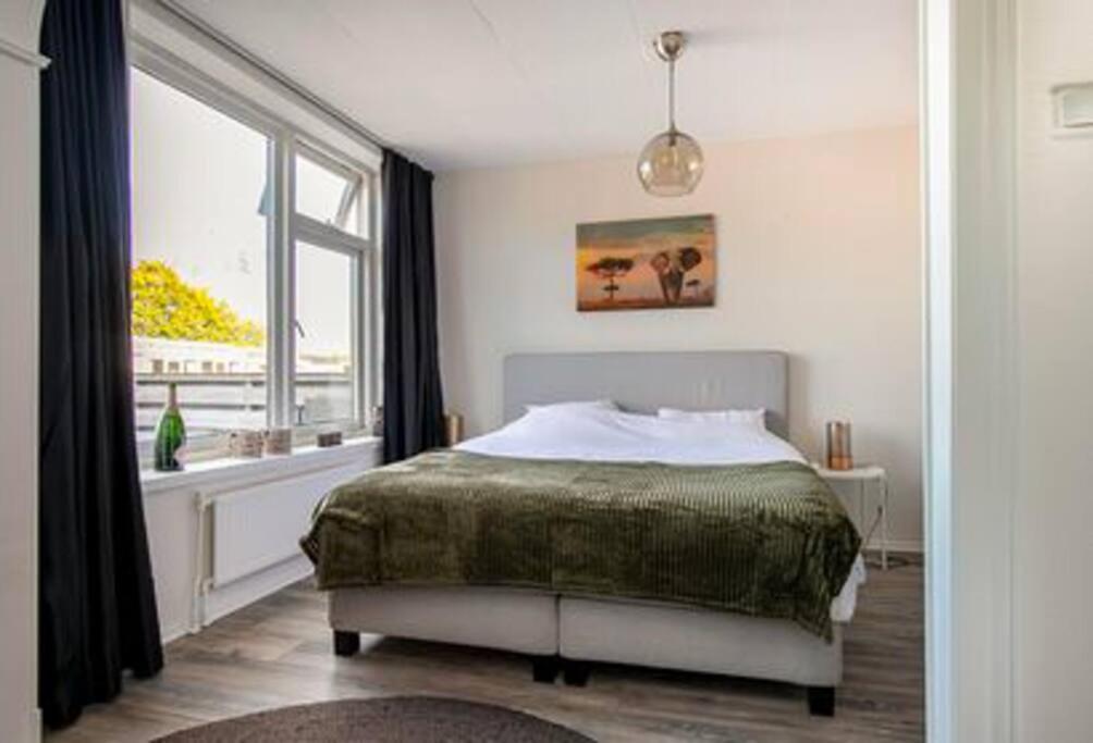 a bedroom with a bed and a large window at Een heerlijke woning op loopafstand van centrum! in Leeuwarden