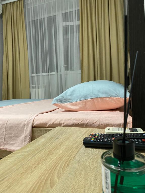 Schlafzimmer mit einem Bett und einem Tisch mit Fernbedienung in der Unterkunft 1 комнатная квартира в ЖК Арман в самом центре города in Aqtöbe