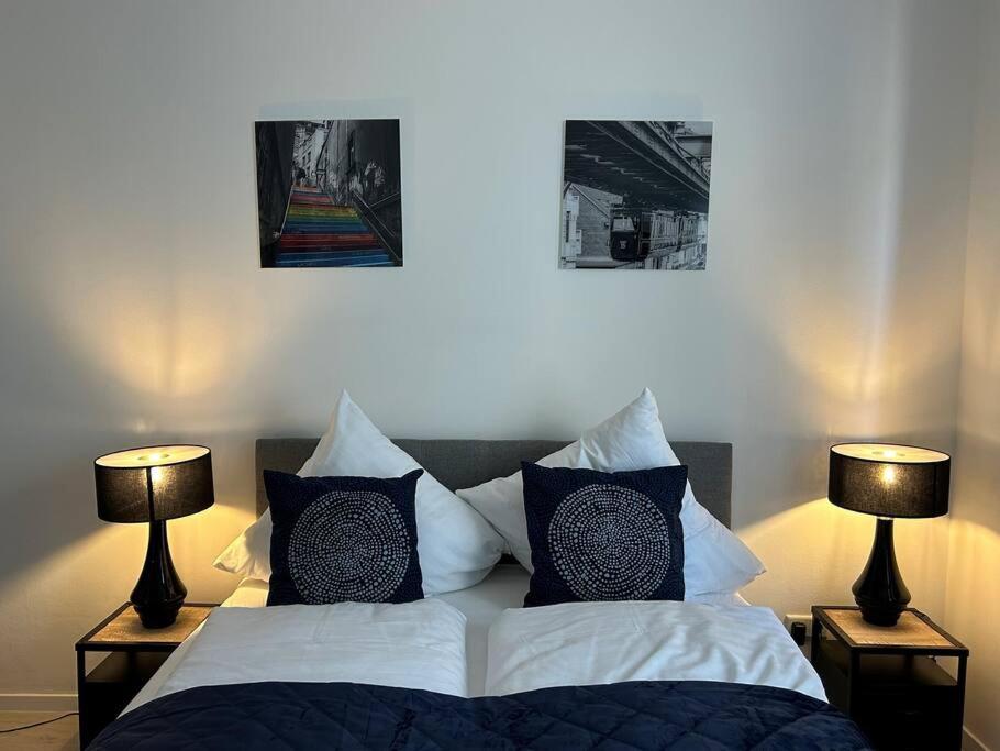 um quarto com uma cama com almofadas e 2 candeeiros em Gemütliche 2-Zimmer Wohnung - Zentral - Netflix em Wuppertal