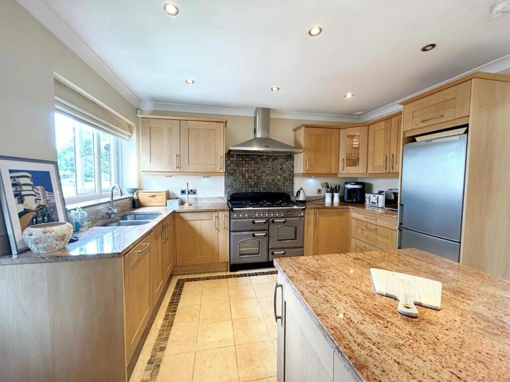 uma cozinha com armários de madeira e electrodomésticos de aço inoxidável em 3 Chatsworth Road, Worsley em Manchester