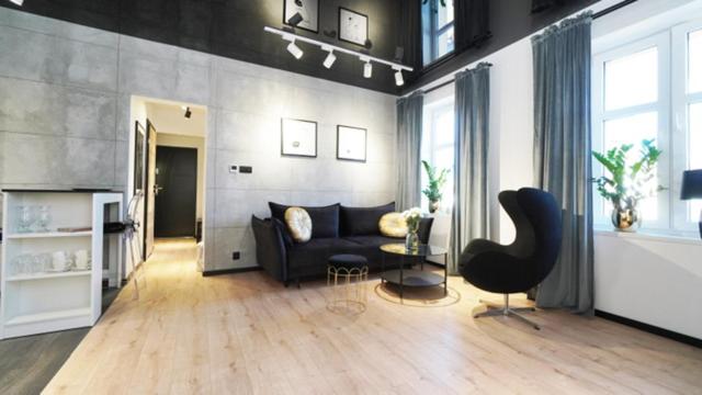 a living room with a black couch and a chair at Przytulny elegancki APARTAMENT przy dworcu in Elblag