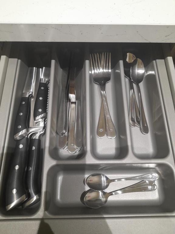 a sink with silver utensils in a drawer at Kirkcudbright Holiday Apartments - Apartment D in Kirkcudbright