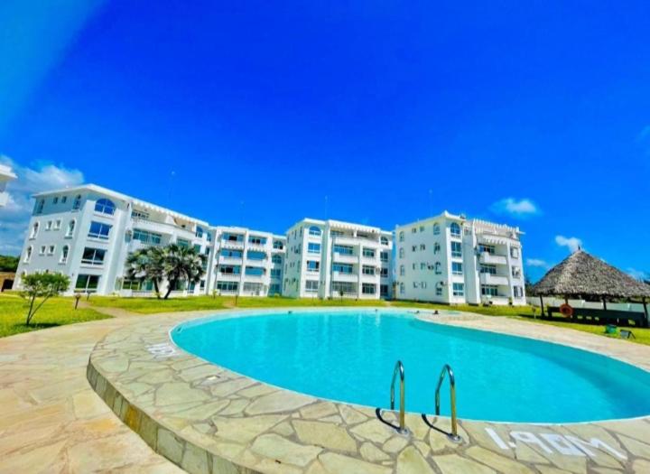 a swimming pool in front of some apartment buildings at Wanderstay Vacation Homes in Malindi