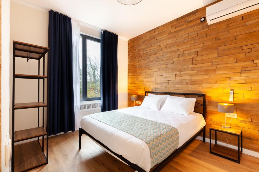 een slaapkamer met een bed en een houten muur bij Renovated 3-bedroom House in Nature - Iskia Estate in Martvili