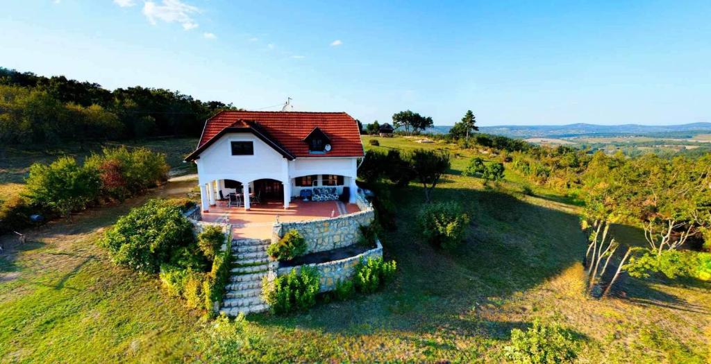 une petite maison blanche avec un toit rouge sur un champ dans l'établissement Dorono House, à Balatonudvari