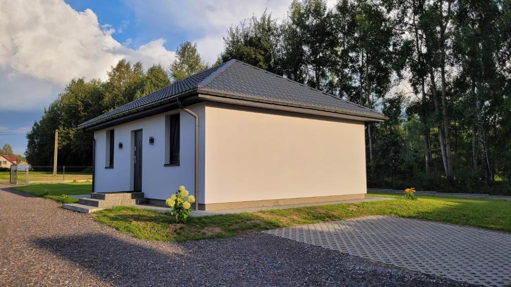 a smallshed with a white building in a yard at Domek Ewy in Święta Katarzyna