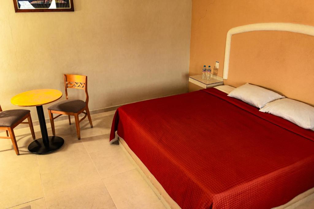 a bedroom with a red bed and a table and chair at Villa Meztli in San Juan Teotihuacán
