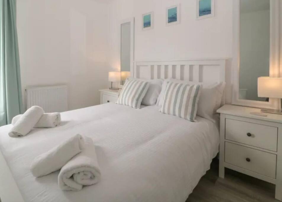 a bedroom with a white bed with towels on it at Sandown - 2 minutes walk to the Downs, Restaurants Bars & Beaches in Torquay