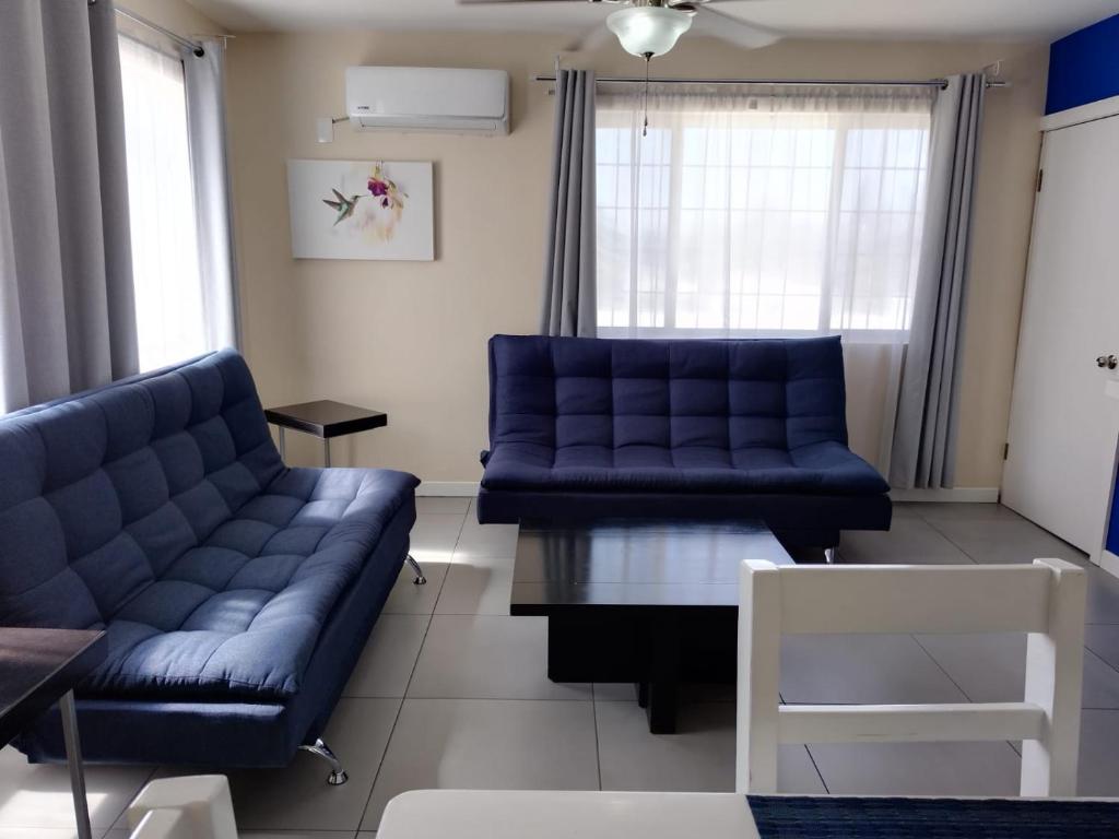 una sala de estar con 2 sofás azules y una mesa. en Departamento moderno en Ciudad Juárez