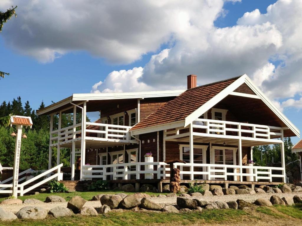 Cette grande maison en bois est dotée d'une balustrade blanche. dans l'établissement Luobos vienkiemis, à Luoba