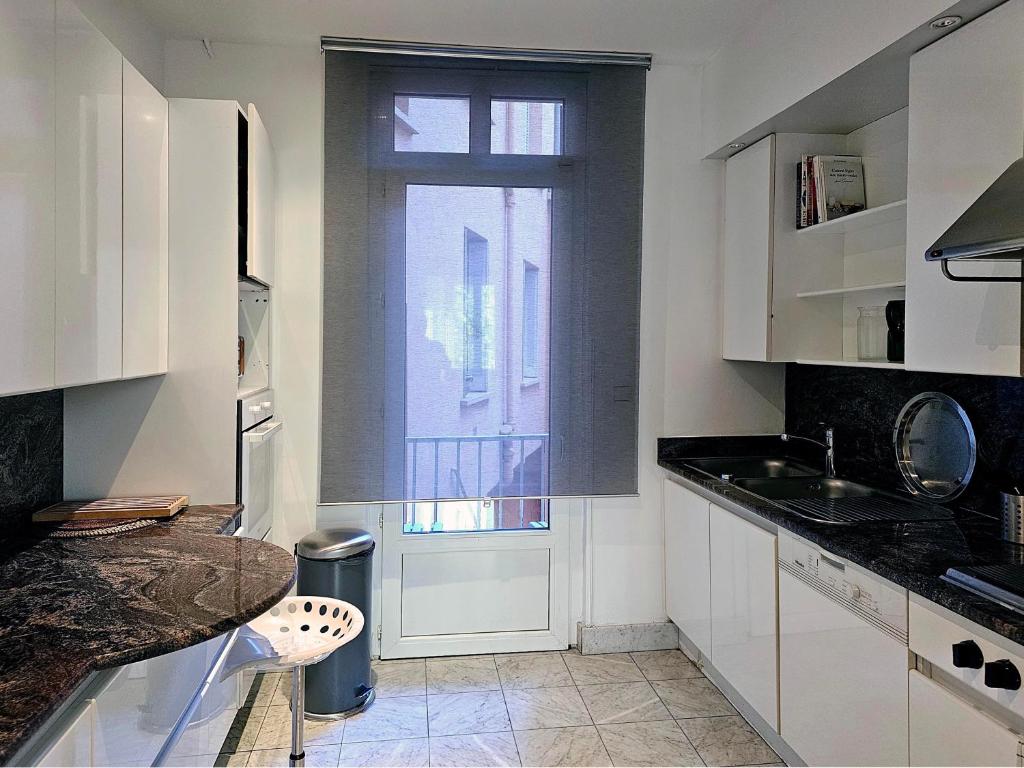 a kitchen with white cabinets and a window and a counter at L&#39;Idrac, Appartements en Hyper centre in Toulouse