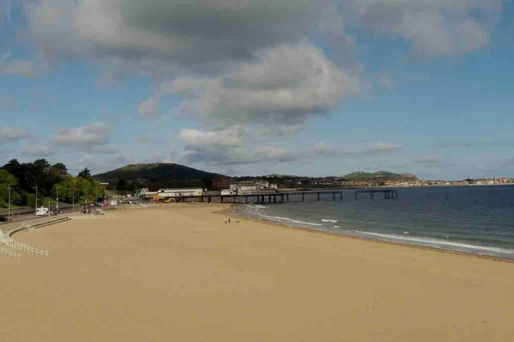 a sandy beach with a pier in the water at Modern 5 Bedroom Terraced Luxurious House in Colwyn Bay