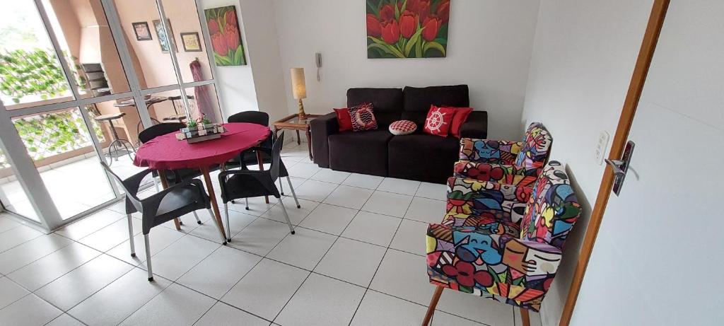 uma sala de estar com uma mesa e um sofá em Apto Ubatuba Home - Eloisa 114 em Ubatuba