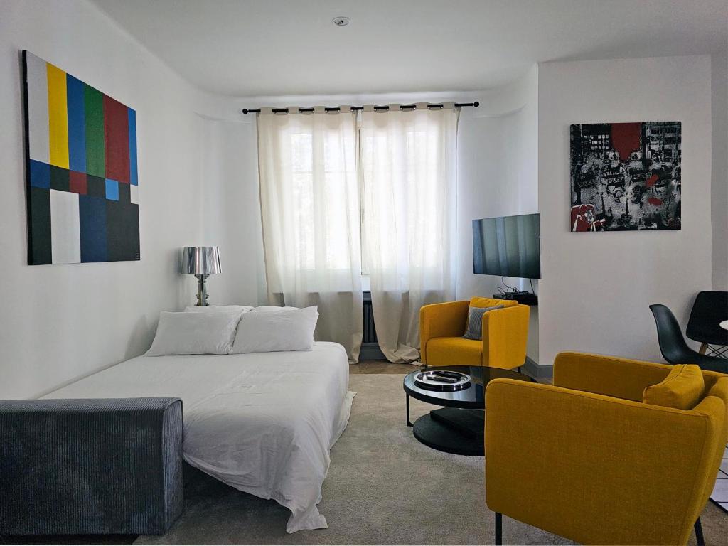 a bedroom with a bed and two chairs and a television at L&#39;Idrac, Appartements en Hyper centre in Toulouse
