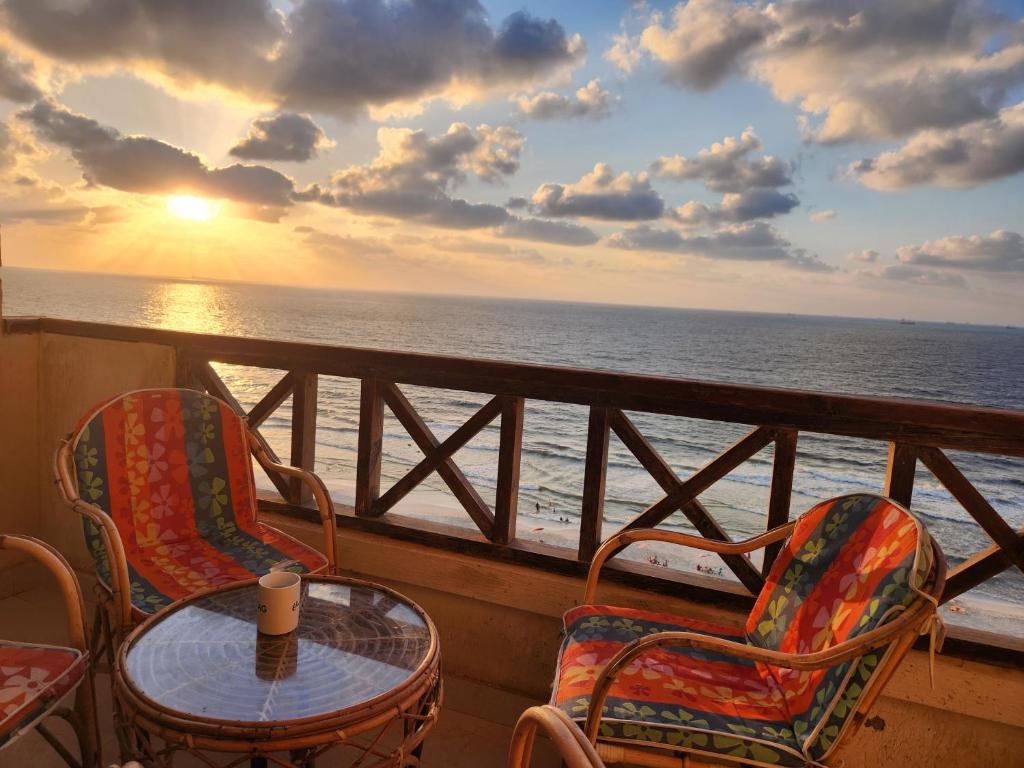 een tafel en stoelen op een balkon met uitzicht op de oceaan bij شقة مصيف الاسكندرية - البيطاش بيانكي in Alexandrië