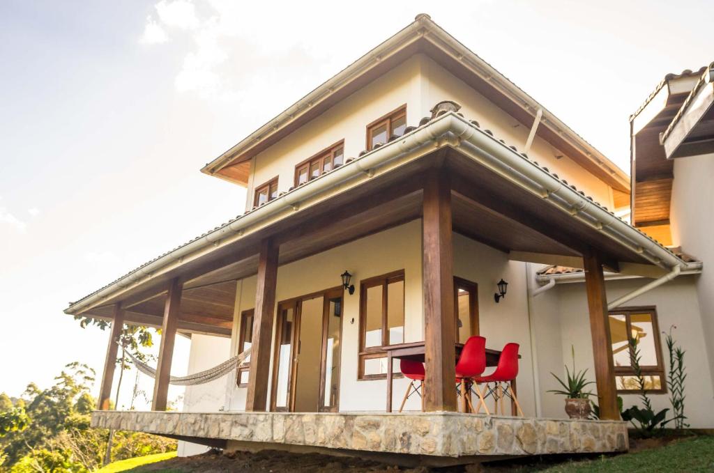 a house with red chairs on the porch at Vista para Pedra Azul - 15pessoas 5qtos 7camas 4banheiros - Adelta hospedagem in Venda Nova do Imigrante