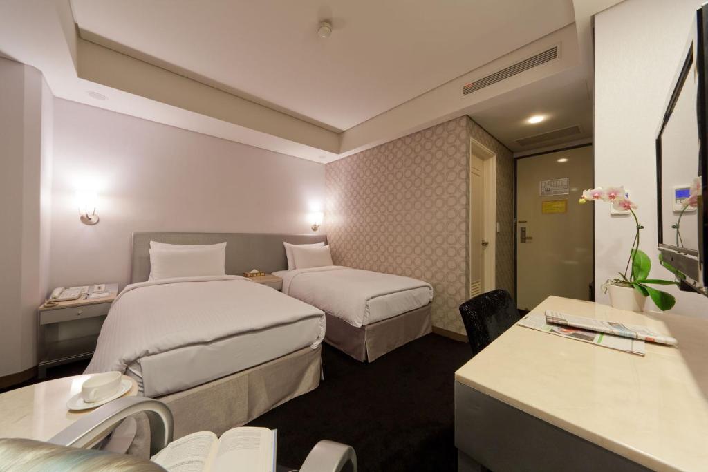 a hotel room with two beds and a desk at Harbor View Hotel in Keelung