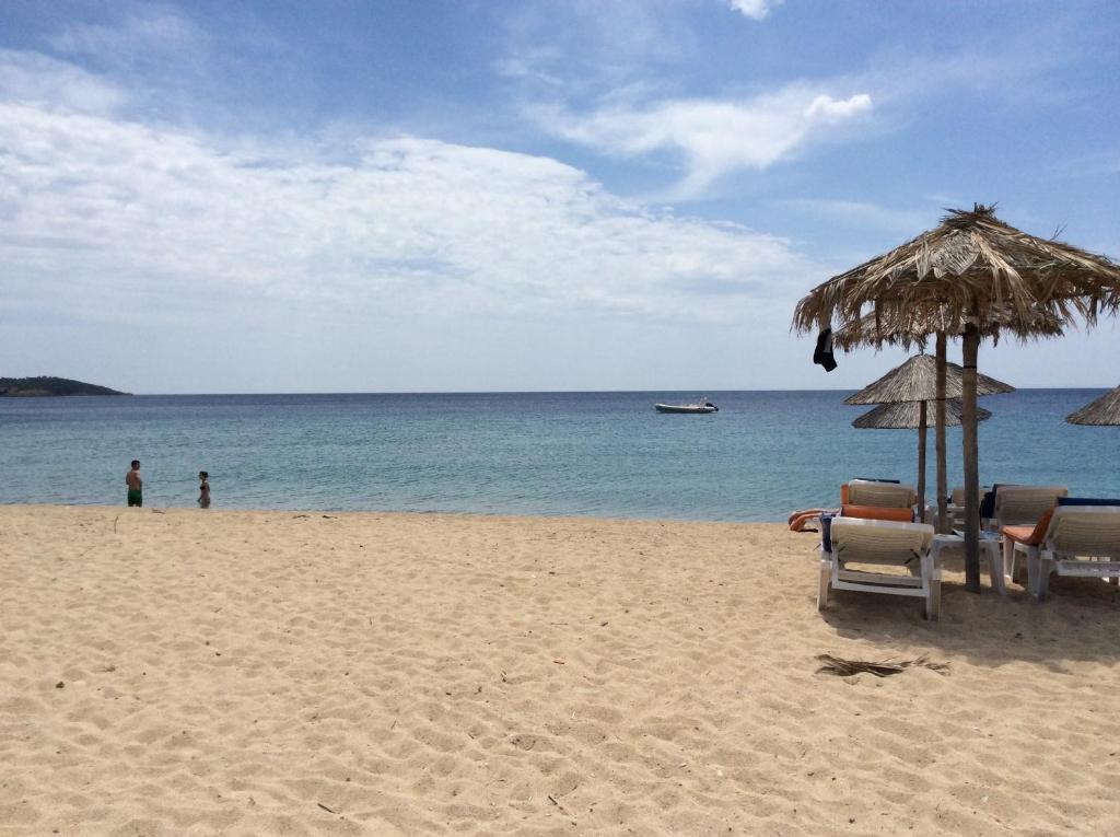 una playa con sillas y sombrilla y el océano en Toroni Luxury Villas, en Toroni