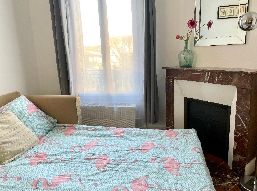 a bedroom with a bed with pink flowers on it at Maison confortable avec jardin à 2 pas de Paris in Fontenay-sous-Bois