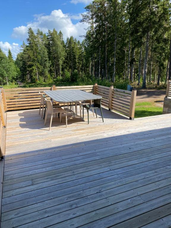 une table de pique-nique et des bancs sur une terrasse en bois dans l'établissement Stuga på ö / närhet till vatten, à Mariestad