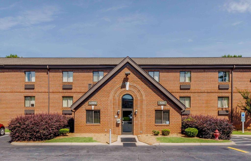 a red brick building with a door in a parking lot at Extended Stay America Select Suites - Greenville - Haywood Mall in Greenville