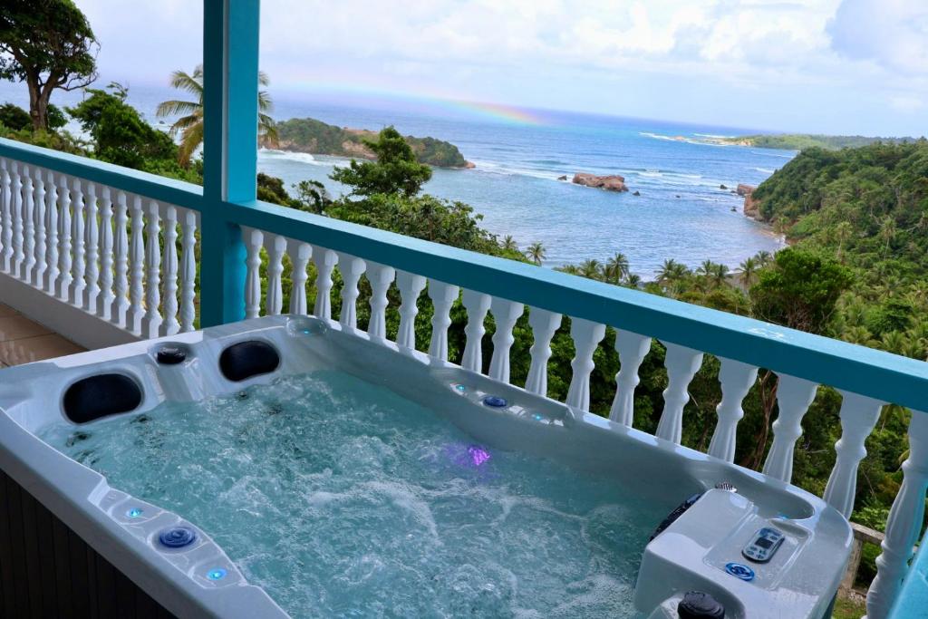 a hot tub on a balcony with a view of the ocean at Blue Whale Villa - Penthouse in Calibishie
