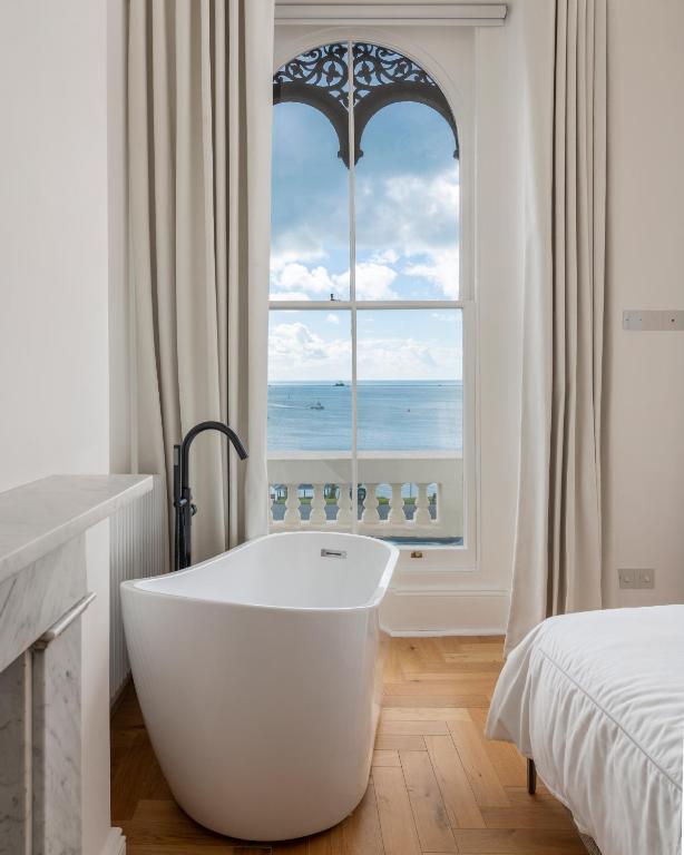 a white bath tub in a room with a window at FOX ON THE HOE - Luxury Apartment accommodation in Plymouth