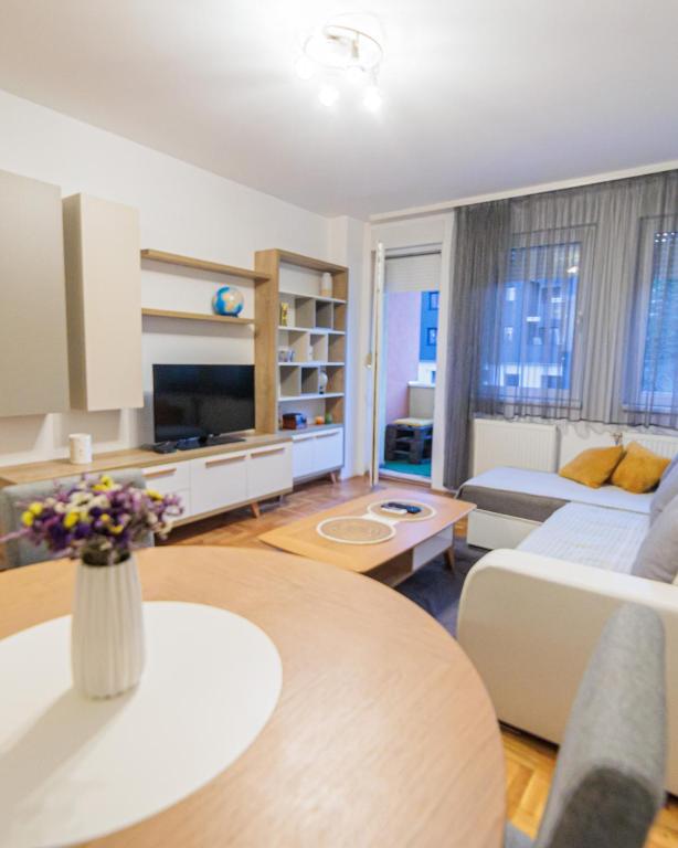 un soggiorno con divano e tavolo di City Center Family Apartment Novi Sad a Novi Sad
