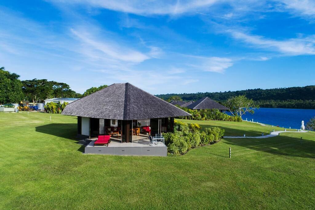 a small hut with a thatched roof on a grass field at Private Island Stay in Vitouara