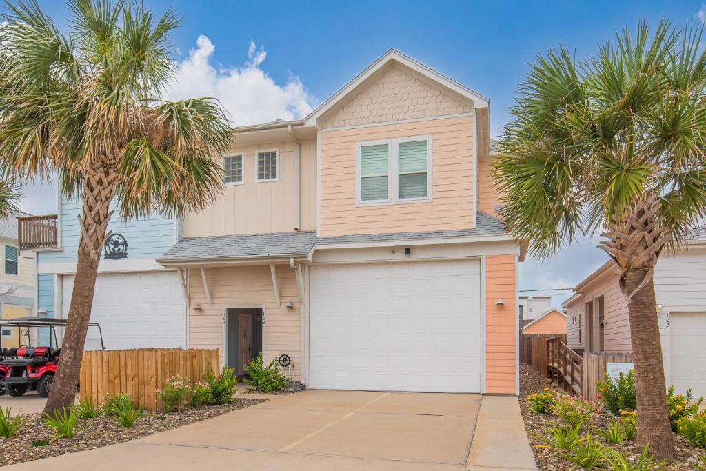 une maison avec des portes de garage blanches et des palmiers dans l'établissement Bird in Paradise, à Port Aransas