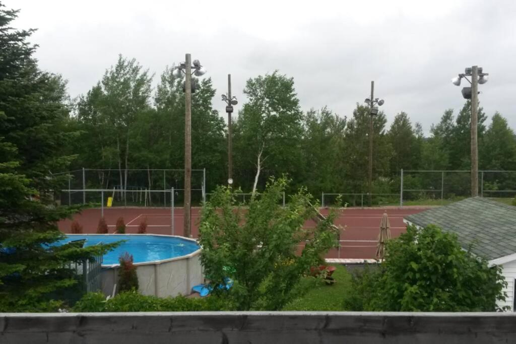 a tennis court with a pool and a tennis court at Logement avec stationnement tennis et piscine in Saguenay